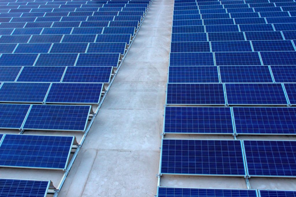 Image shows long rows of blue solar panels laid out on a stone floor.